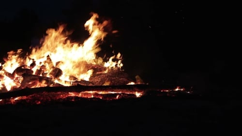 Großes Lagerfeuer aus Ästen brennt nachts im Wald