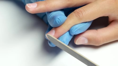 Der
Manikürist behandelt einen Nagel des Kunden mit einer Nagelfeile.