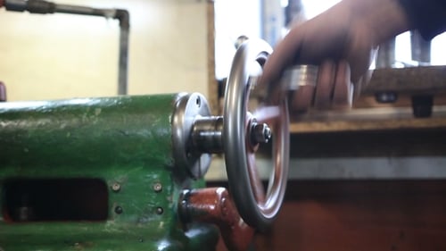 Hand Spins Wheel on Vintage Green Metal Lathe