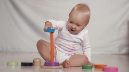 Adorable Infant Playing with Colorful Wooden Stacker Toy