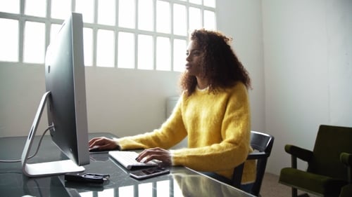 Attraktive schwarze Frau arbeitet am Computer im Büro
