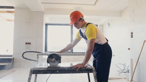 Young Adult Cuts Tile with Wet Saw