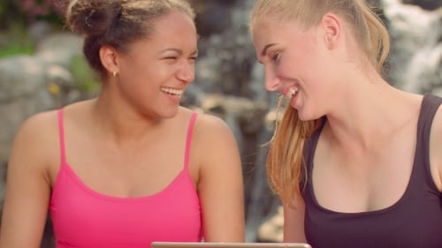 Two Friends Smiling Looking at Tablet Outdoors