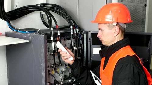 Der Techniker passt das Gerät mit der Fernbedienung an. Ingenieur arbeitet und schreibt auf einem Papier.