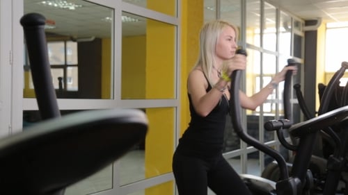 Young Woman Exercising On Elliptical Trainer