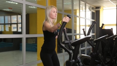 Hübsches Mädchen trainiert auf speziellen Sportgeräten im Fitnessstudio