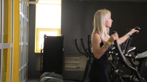 Young Woman Exercising On Elliptical Trainer