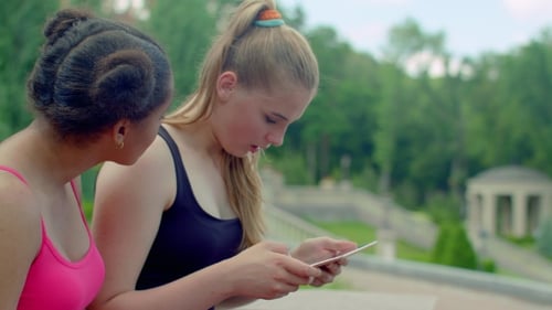 Two Young Adults Using a Tablet in the Park