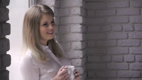 Smiling Woman Holding Mug by Window
