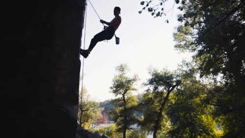 Silhouette Of Man Climbing On Cliffed Rock Belay