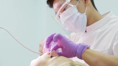 Dentist Performing Procedure on Patient's Teeth in Clinic