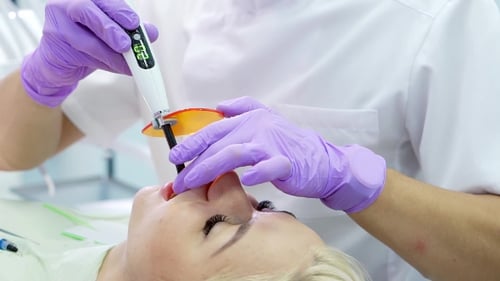 Dentist Using Curing Light on Woman's Teeth