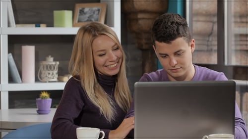 Couple Looks At The Laptop At The Cafe