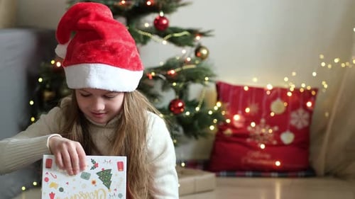 Girl Opening Christmas Gift By Christmas Tree