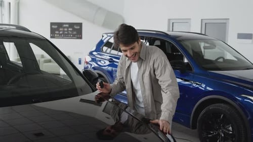 Happy Man Holding Keys of New Car and Smiling to Camera Enjoying Vehicle Purchase in Dealership