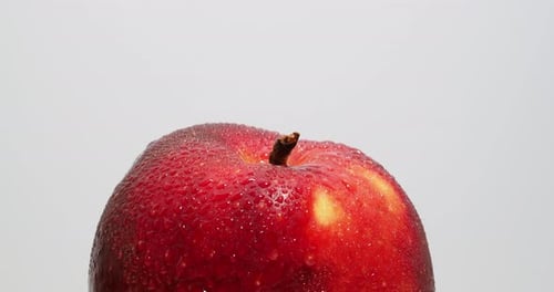 Reifer roter Apfel mit Wassertropfen rotiert auf weißem Hintergrund