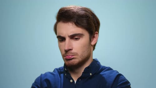 Unhappy Man Looking at Camera on Blue Background. Upset Man Posing in Studio