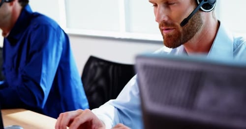 Male executive with headset working on computer