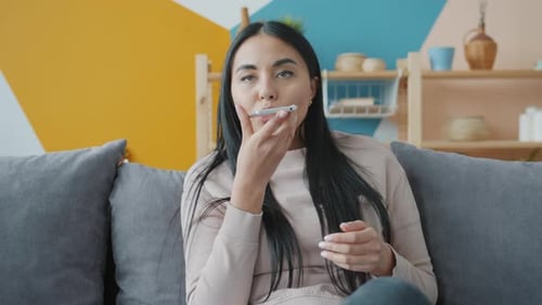 Woman Using Smartphone at Home on Sofa