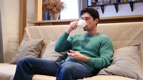 Man Relaxing on Couch Drinking Coffee Indoors