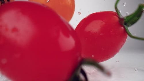 Kamera verfolgt Kirschtomaten, die auf die Wasseroberfläche fallen Zeitlupe.