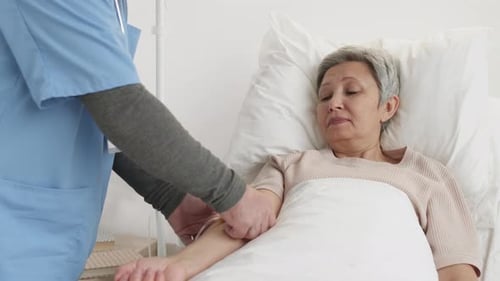 Unrecognizable Doctor Connecting IV to Female Patient Arm