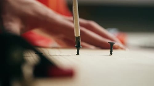 Hands Drive Screw Into Piece of Wood