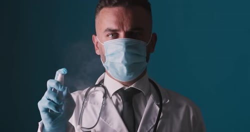 Studio Portrait of Medical Doctor in Protective Mask and Glove Spraying Alcohol Sanitizer To Camera