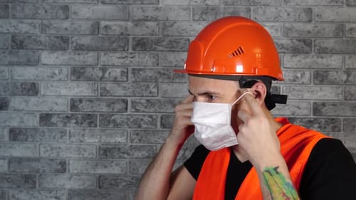 Man Adjusts Face Mask with Hardhat