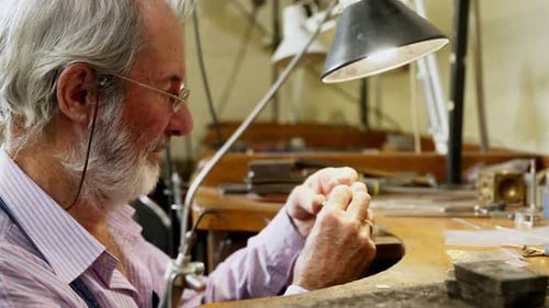 Goldsmith working at table in workshop