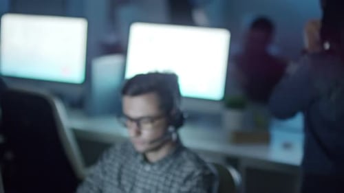 People with Headsets Working in Dark Office