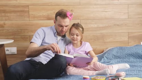 Dad and Daughter Reading a Book Together on Bed
