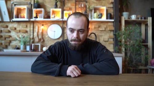 Pensive Man Sitting at Table with Hands on Face