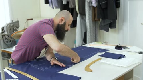 Tailor Cutting Blue Cloth in Bright Workplace