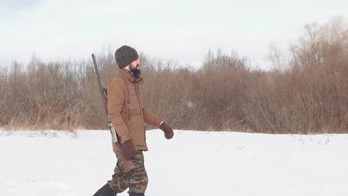 Young Hunter in Warm Clothes Is on the Field with a Hunting Rifle.
