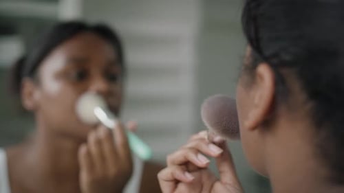 Woman Applying Makeup With a Brush in Bathroom