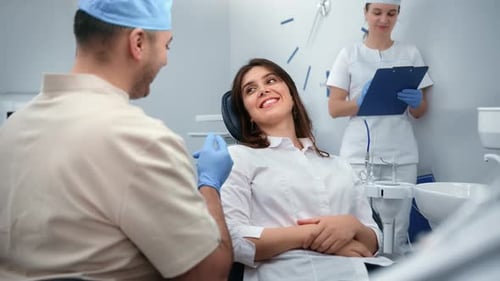 Zahnmedizin Männlicher Arzt und lächelnde Patientin sprechen in der Klinik über Zahnbehandlung
