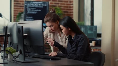 Team of Coworkers Comparing Source Codes Running on Laptop Screen and Computer Monitor