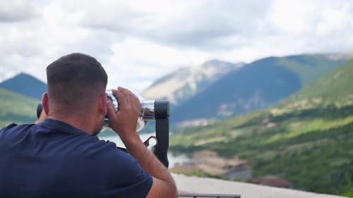 Man Gazing at Mountain View with Coin Binoculars