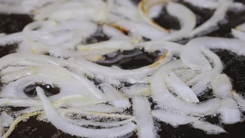 Sliced White Onions Frying Into Hot Pan with Oil