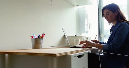 Woman Working at Desk with Laptop and Phone