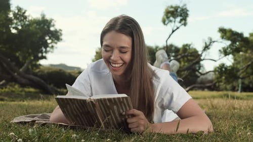 Woman Reading Book Lying on Lawn