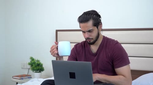 Jeune homme indien sérieux travaillant à domicile sur un ordinateur portable