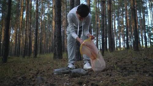 Volunteer with Garbage Bags Cleaning Forest