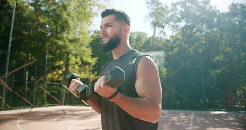 Sporty Man Lifting Weights with Both Hands in a Public Park Biceps Training