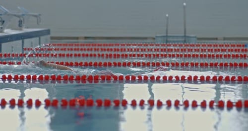 Schwimmerin beginnt mit Brille im Pool zu schwimmen und eine Wasserkappe wird von der Seite gedrückt