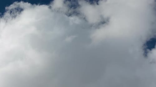 Fluffy White Clouds Drifting Across Blue Sky