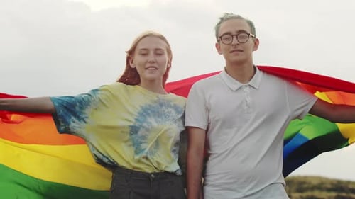 Happy Couple Displaying Rainbow Flag Outdoors