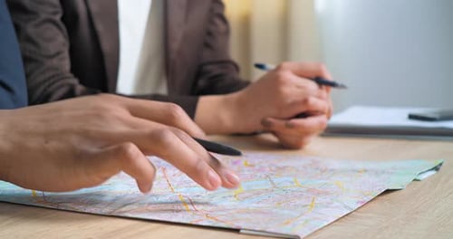 Closeup Male and Female Hands Holding Pens and World Map in Office Two Partners Businesspersons