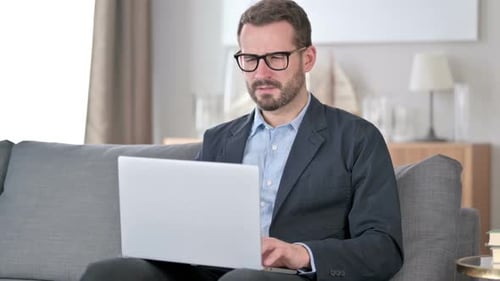 Man Using Laptop on Couch Experiences Back Pain